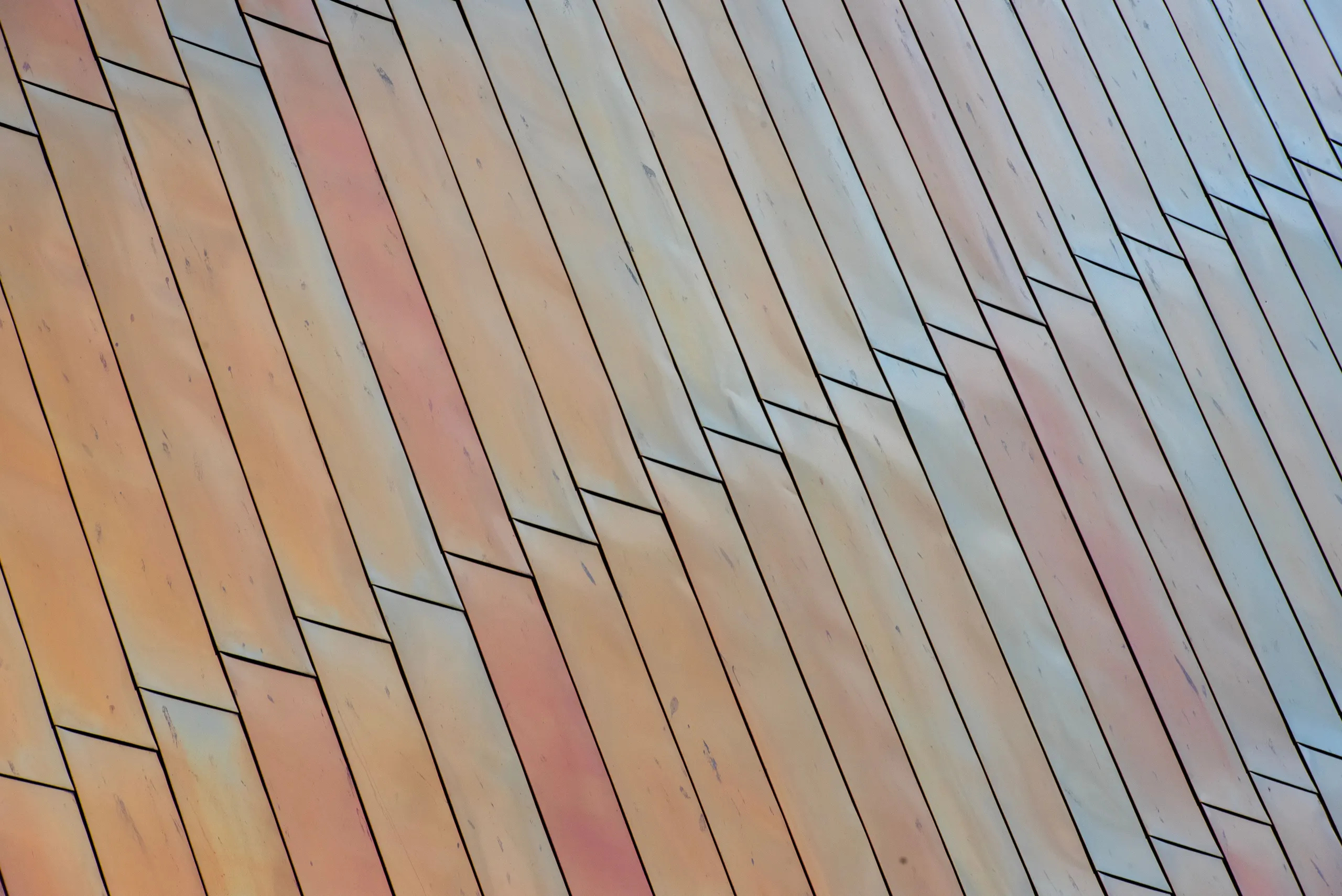 Rivestimento in lastre posate in diagonale, con riflessi dal rame al grigio chiaro